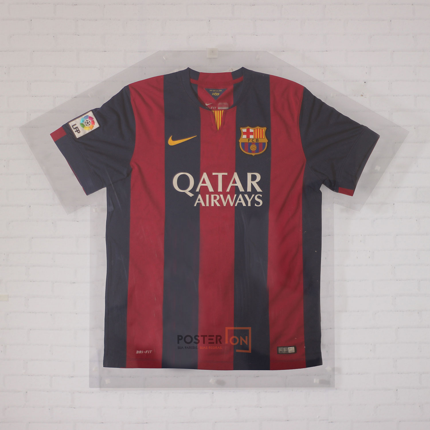 Display expositor de camiseta em acrílico transparente com uma camisa de futebol, pendurado numa parede de tijolos brancos